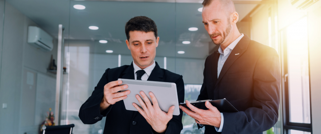 Illustration sur l’analyse des résultats d’une campagne e-mailing : suivi du taux d’ouverture, de clics, de désabonnement et de conversion pour identifier ce qui fonctionne. Les plateformes comme Mailchimp, Sendinblue ou Brevo permettent de visualiser les statistiques en temps réel et d’ajuster les futures campagnes pour une amélioration continue. L'image représente deux hommes qui analysent les résultats.